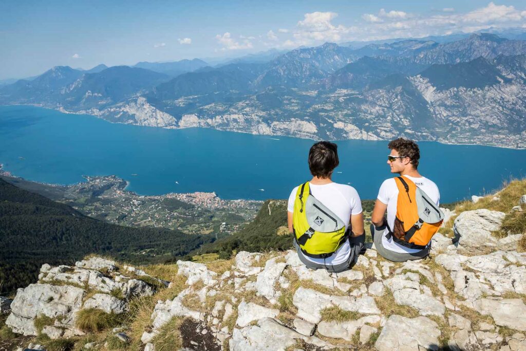 Young men wearing X-over bags overlooking Lake Garda