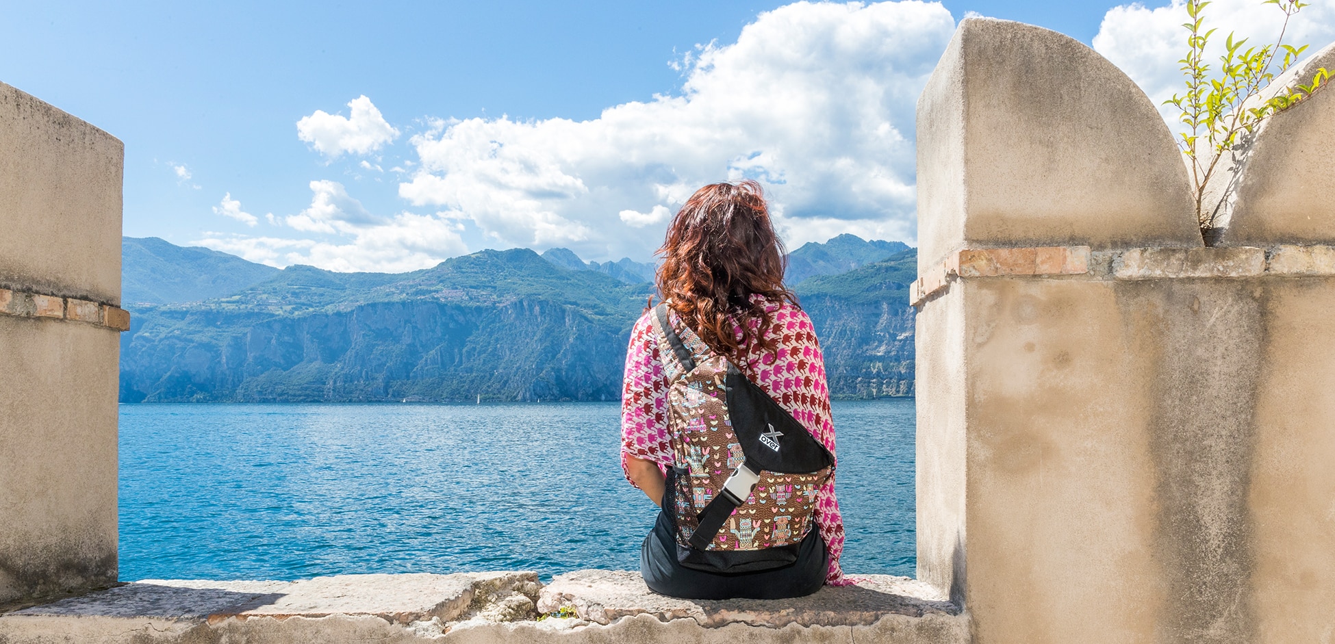 Woman wearing an X-over bag is looking at Lake Garda