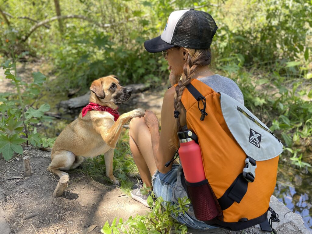 Woman wearing an X-over bag gives her dog a treat