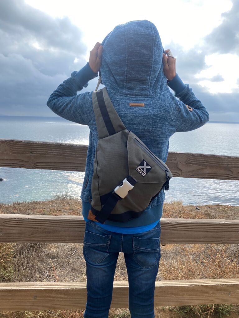 Woman wearing X-over bag looking at ocean horizon